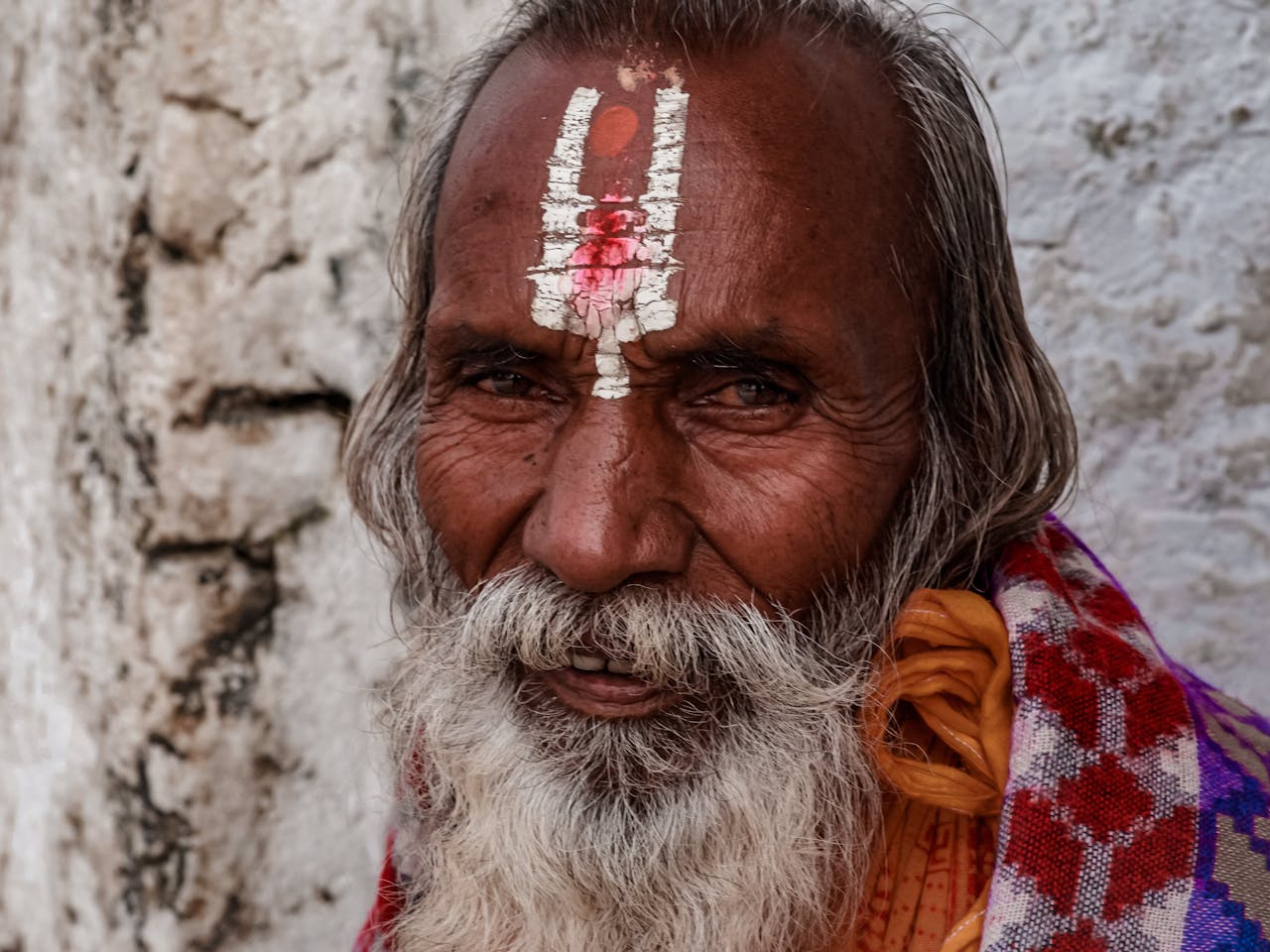 A senior man adorned with a tilak, symbolizing spirituality and tradition.