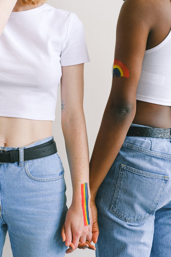 Interracial couple showing love with rainbow body paint, symbolizing LGBTQ pride.