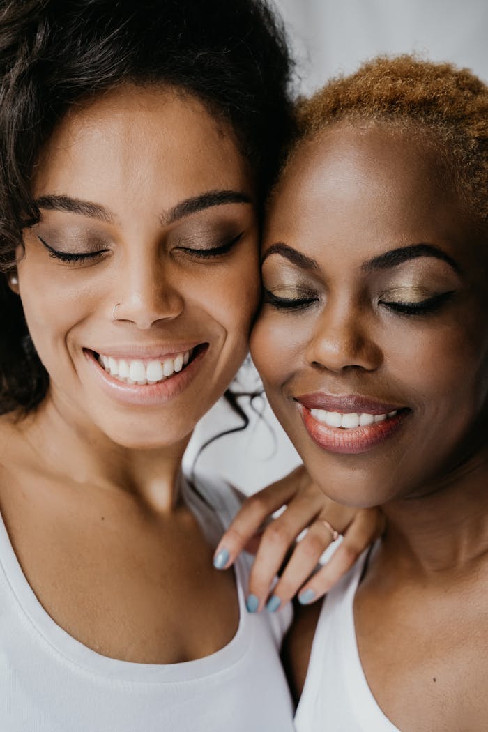 Close-up portrait of two happy women with eyes closed, embracing in friendship.