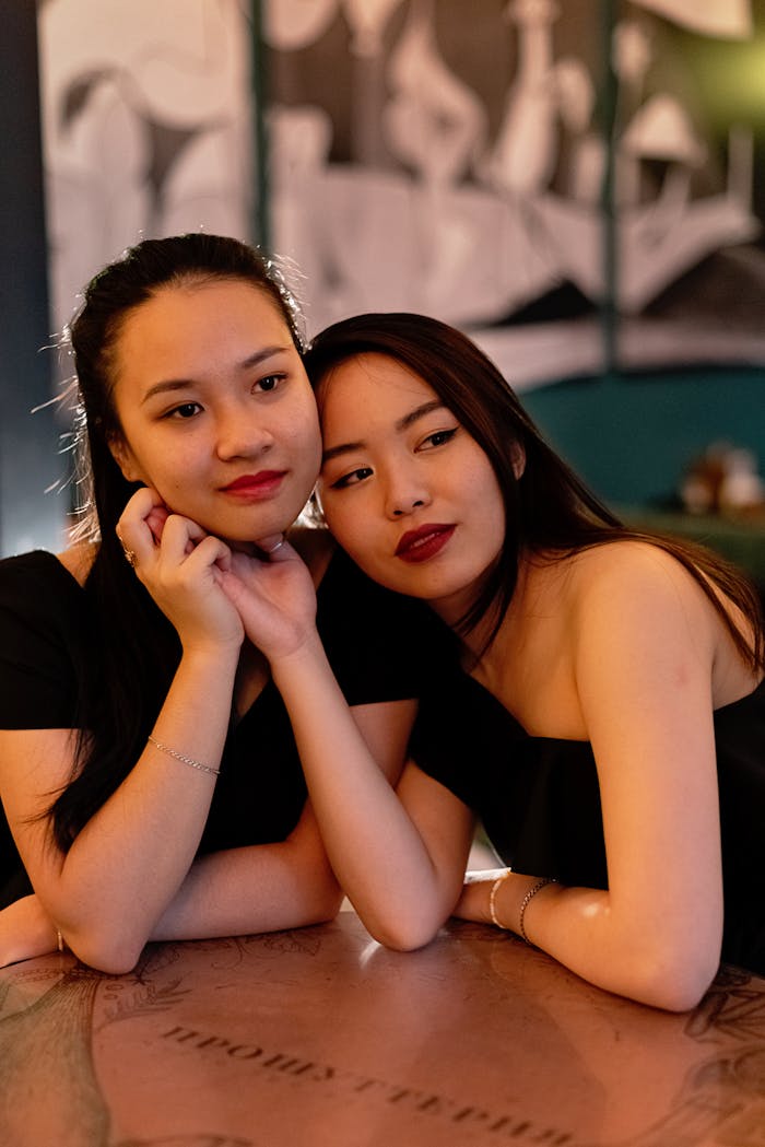 Two young women share a romantic moment indoors, enhancing the theme of love and connection.